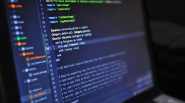 Close-up of a computer screen displaying programming code in a dark environment.