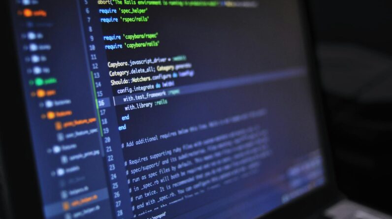 Close-up of a computer screen displaying programming code in a dark environment.